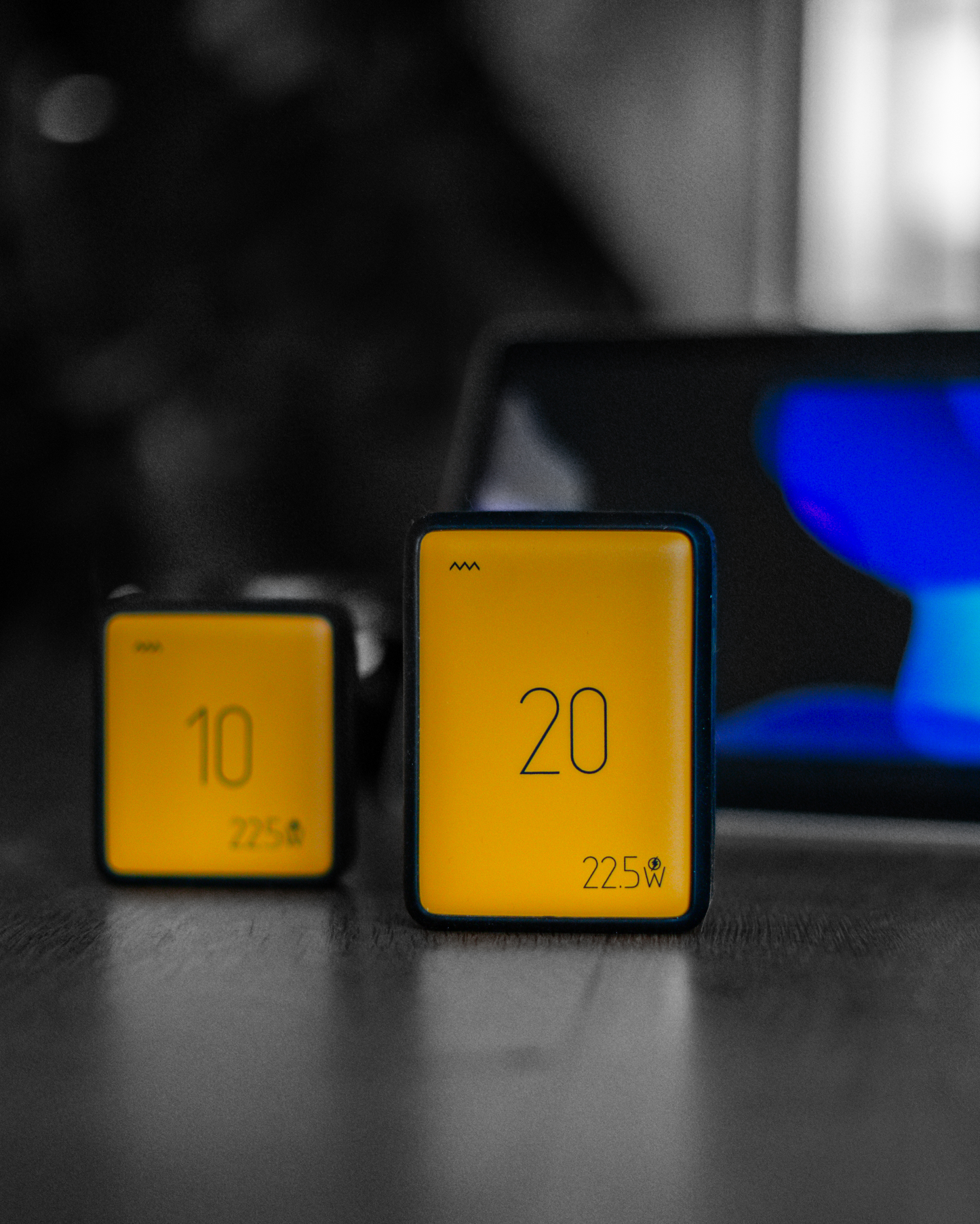 Two powerbanks on a dark surface with a blurred background