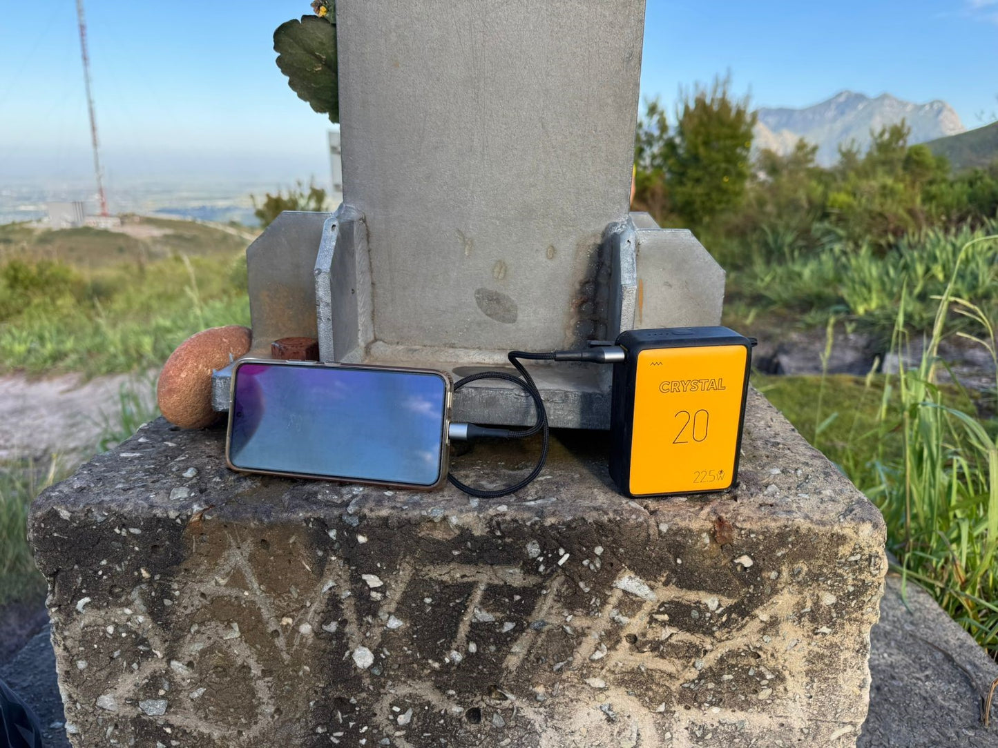 Smartphone and powerbank on a concrete block with a scenic background